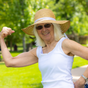 Women smiling outside while flexing arm muscle.