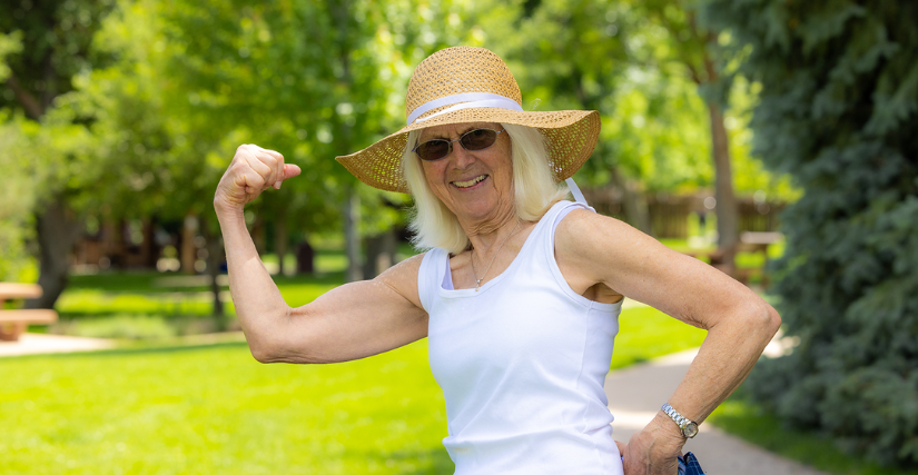 Women smiling outside while flexing arm muscle.